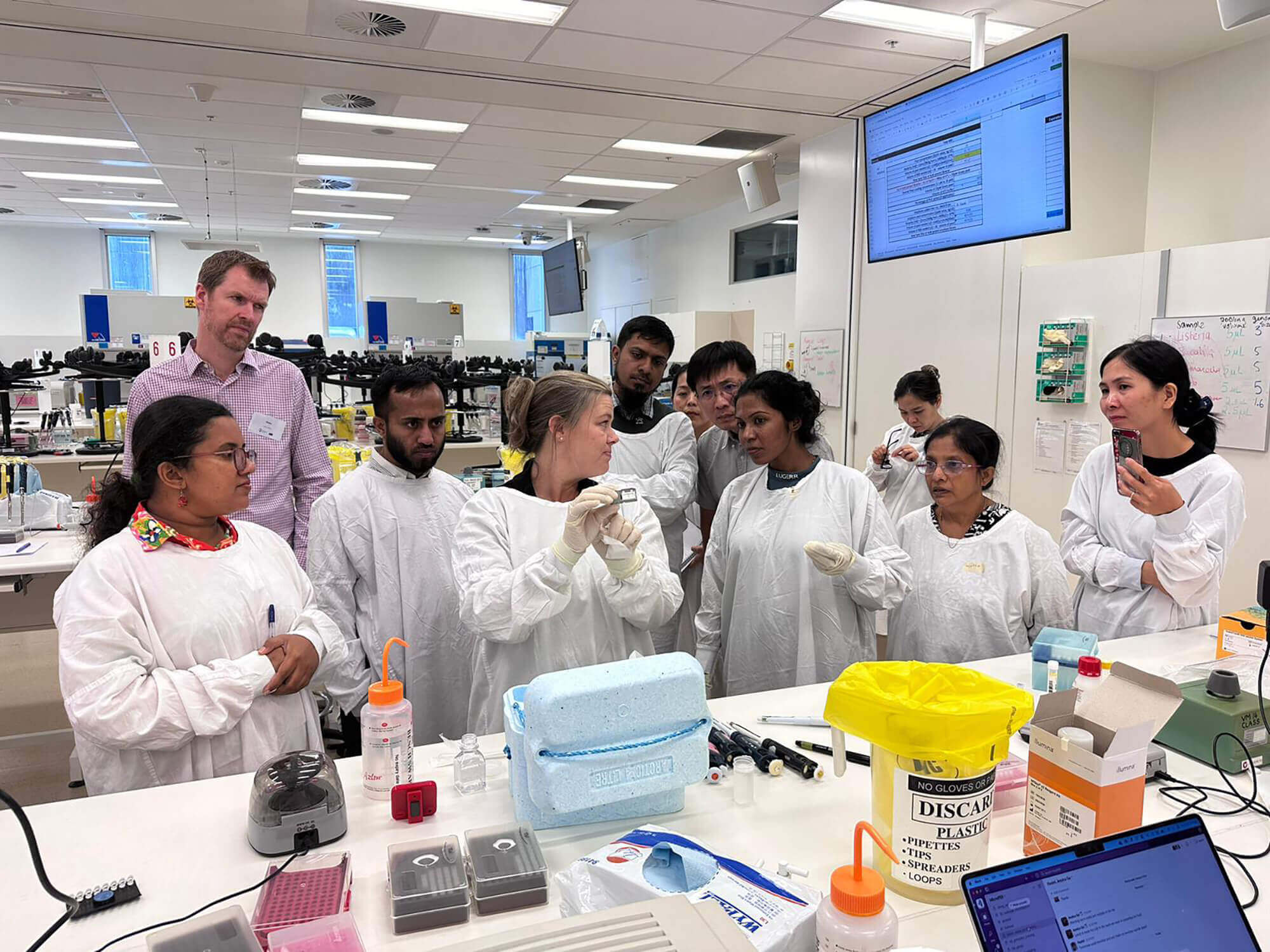 scientists gather around trainer to view specimen at in a global health laboratory training
