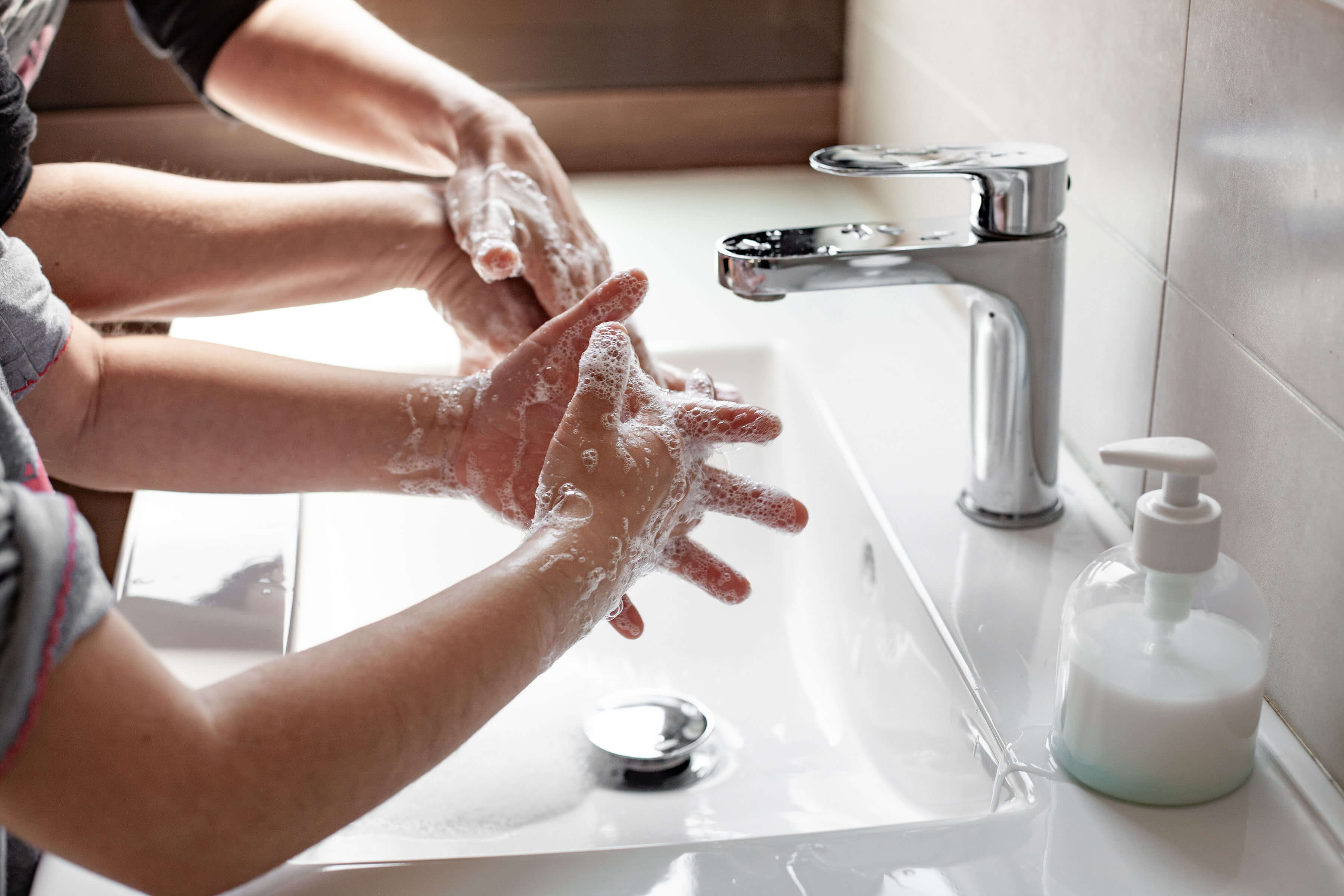 Child washing hands with a parent